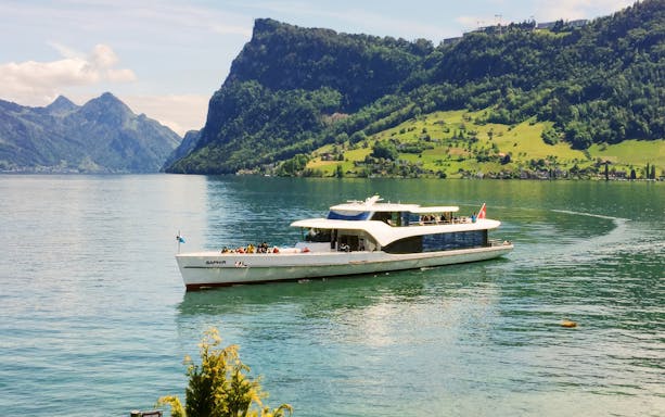 Panorama-yacht Saphir cruising on a scenic lake with mountains in the background.