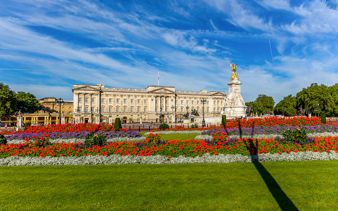 Buckingham Palace exterior with colorful gardens and Victoria Memorial in London.
