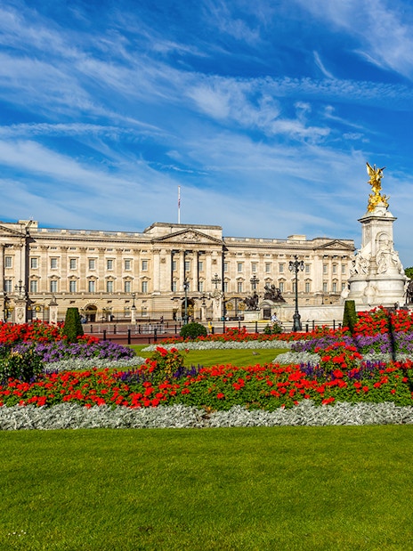 Buckingham Palace exterior with colorful gardens and Victoria Memorial in London.