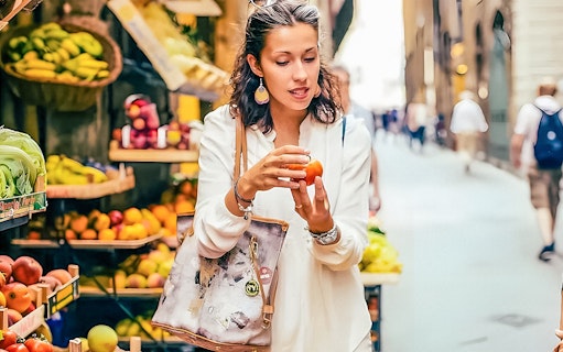 Woman examining produce at a local market in Florence.