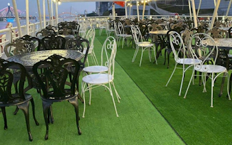 Outdoor dining area on a boat with decorative chairs and tables, view of Han River, Dubai.