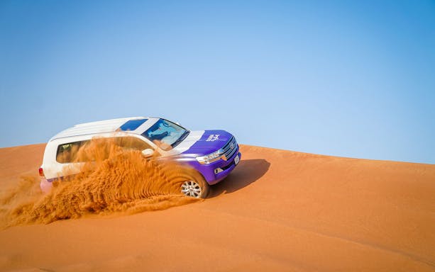 SUV driving over sand dunes in Mleiha during a Fossil Rock tour.
