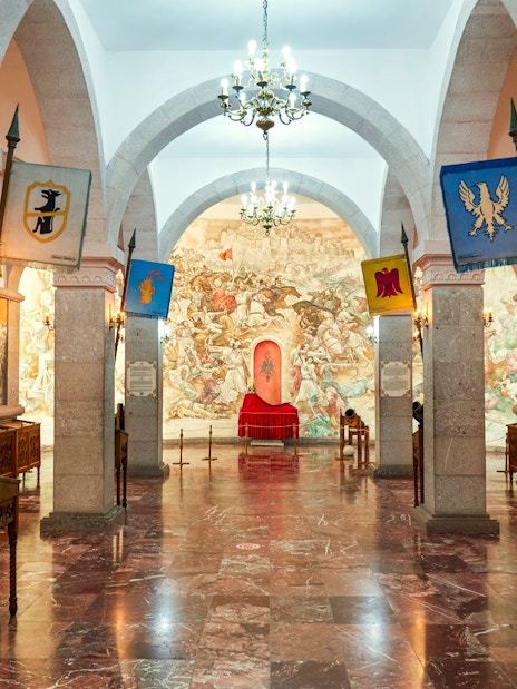 Interior of Skanderbeg Museum at Kruje Castle, Albania, featuring historical murals and flags.