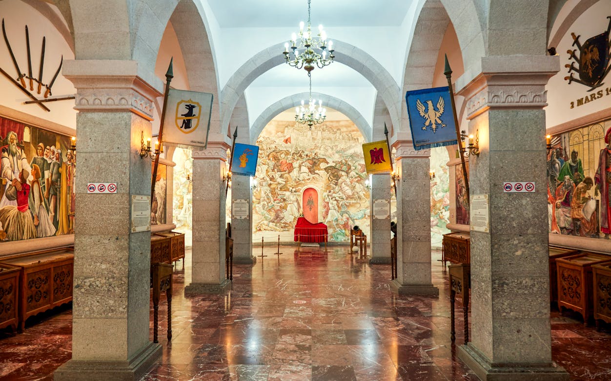 Interior of Skanderbeg Museum at Kruje Castle, Albania, featuring historical murals and flags.
