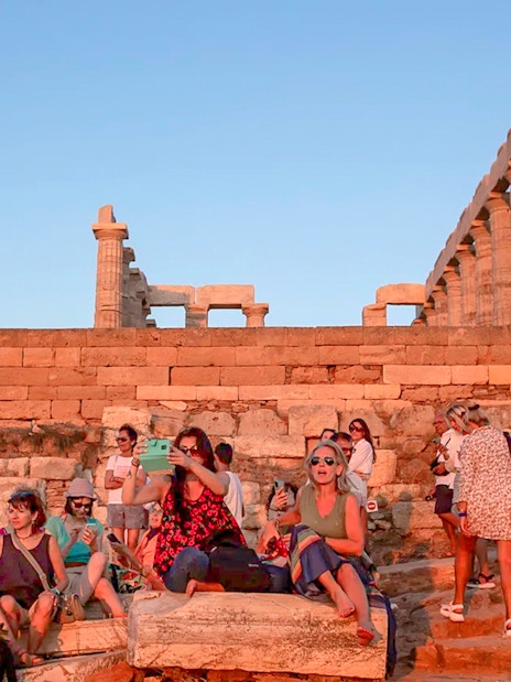 Visitors at Cape Sounion enjoying the sunset near the Temple of Poseidon.