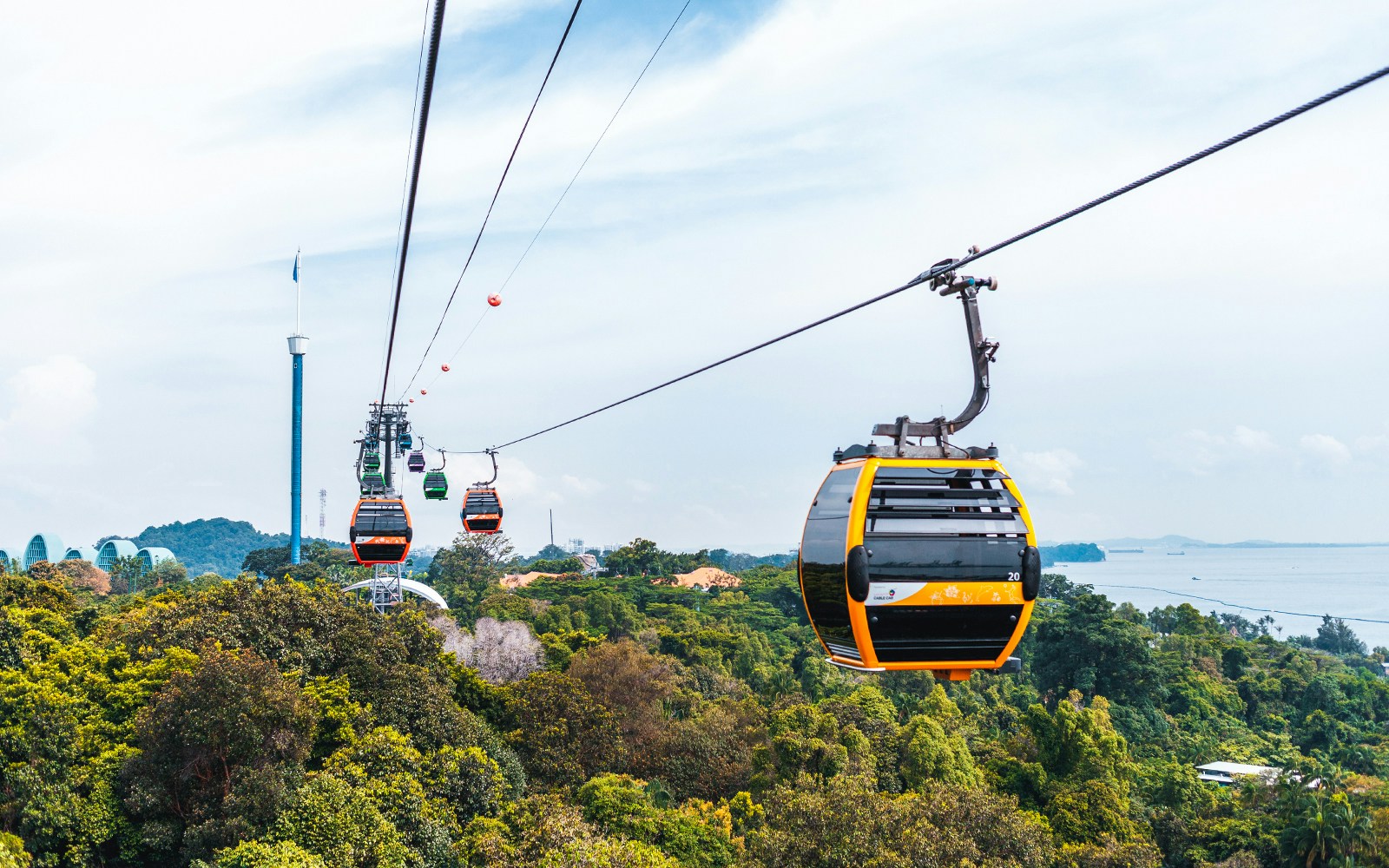 Singapore Cable Car over lush greenery with city skyline in the background.