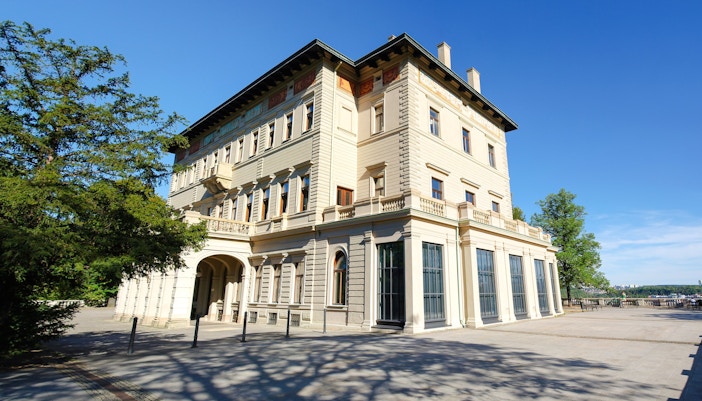 Villa Lützow exterior with trees and clear sky in the background.