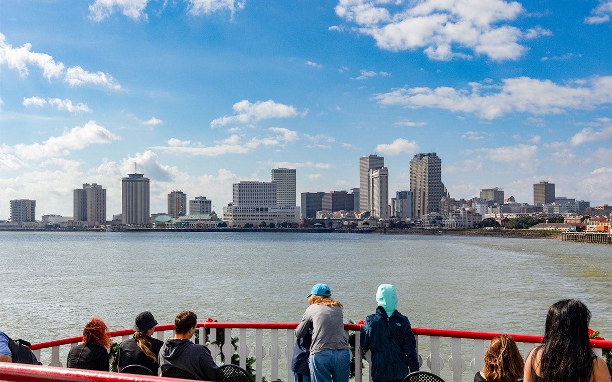 Tourists on Steamboat Natchez deck view New Orleans skyline.