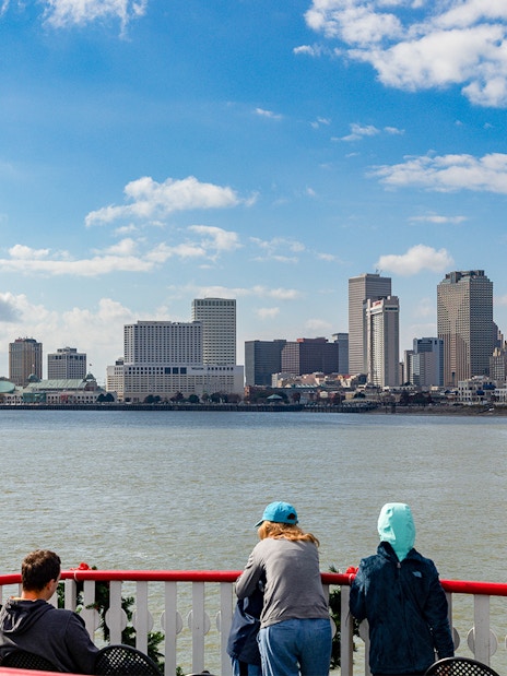 Tourists on Steamboat Natchez deck view New Orleans skyline.