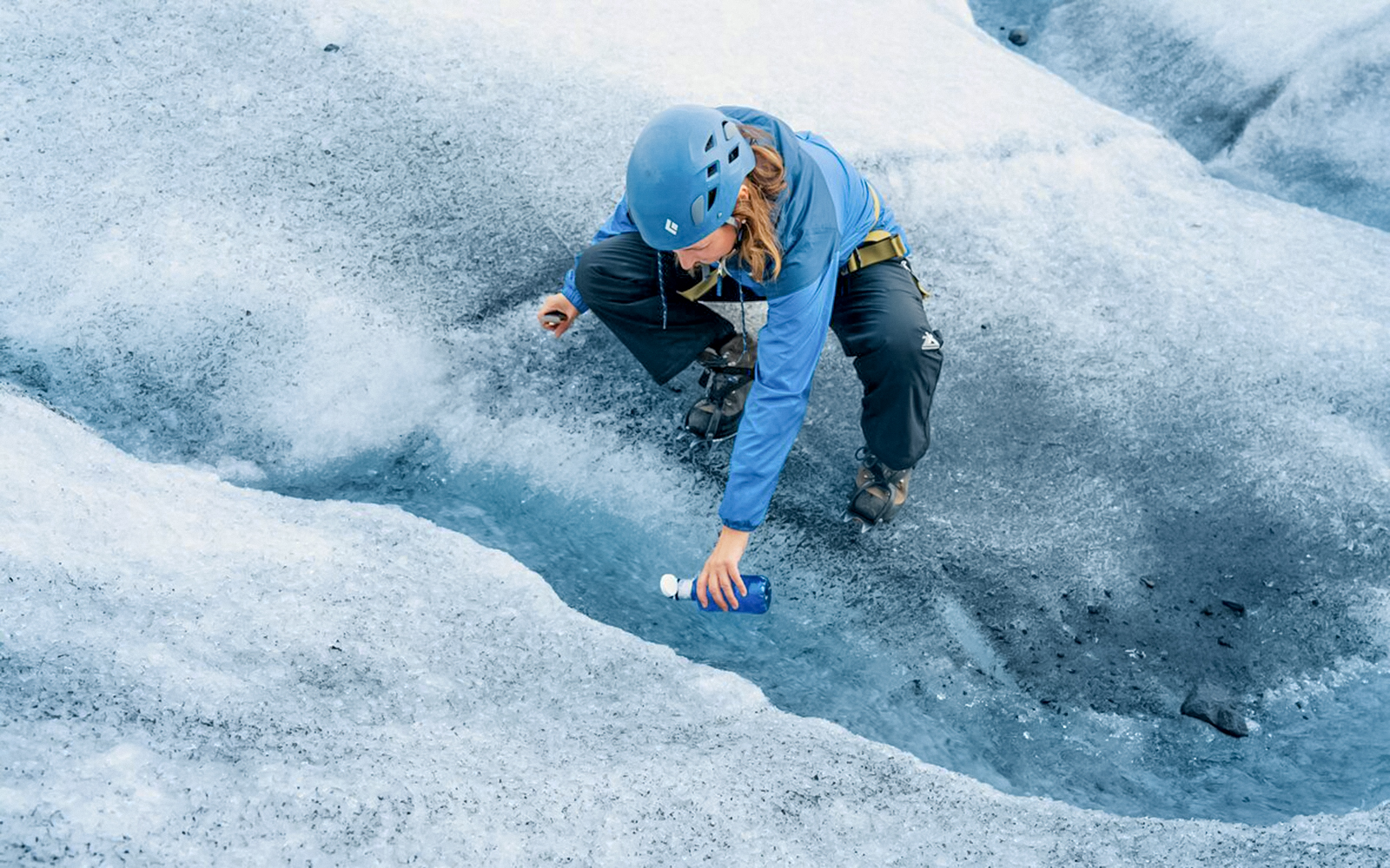 Guest collecting fresh water from glacier crevasse during Ice Maze tour.