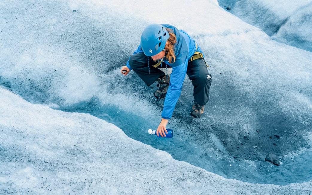 Guest collecting fresh water from glacier crevasse during Ice Maze tour.