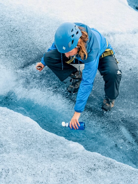 Guest collecting fresh water from glacier crevasse during Ice Maze tour.