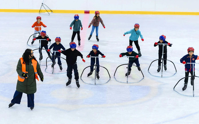 Kids learning to skate at FC Barcelona Ice Rink with instructor guidance.