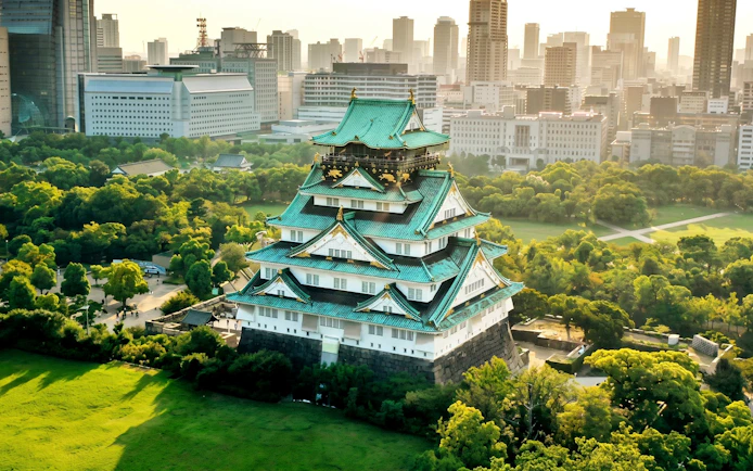 Osaka Castle surrounded by lush greenery and cityscape in Chūō-ku, Osaka, Japan.