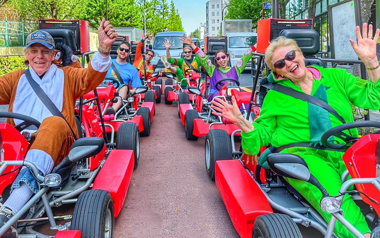 Group enjoying go-kart ride in Shibuya, Tokyo, wearing colorful costumes.