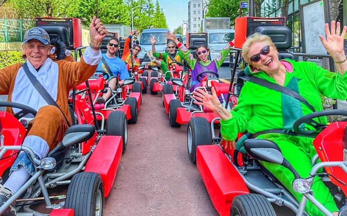 Group enjoying go-kart ride in Shibuya, Tokyo, wearing colorful costumes.
