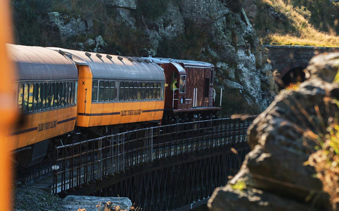 Taieri Gorge train crossing Deep Stream Bridge in scenic landscape.
