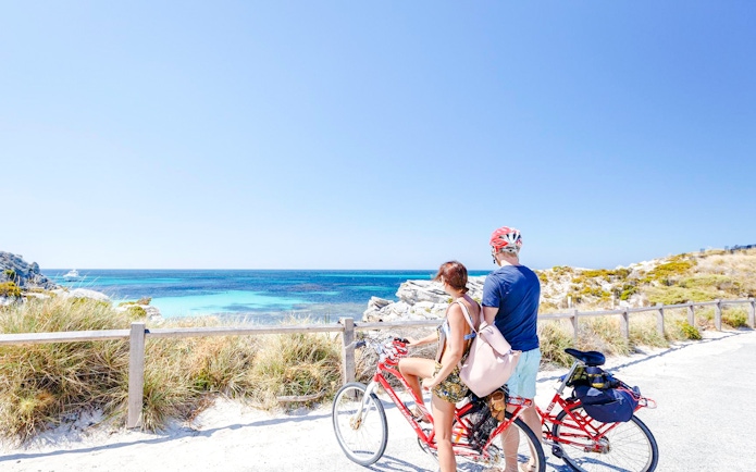 Couple cycling with ocean view on Rottnest Island, Western Australia.