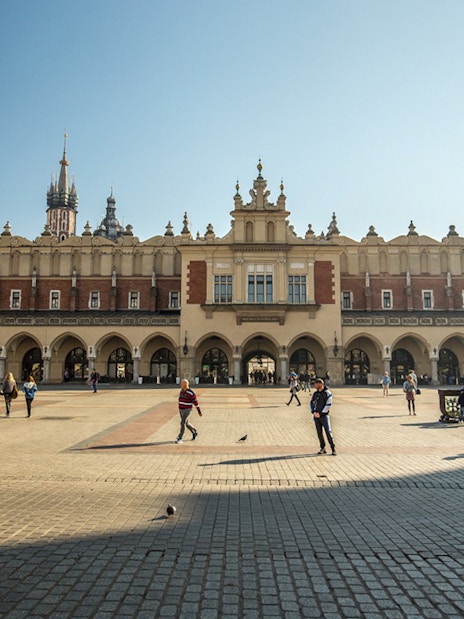 Krakow's Cloth Hall in the Main Market Square with people walking.