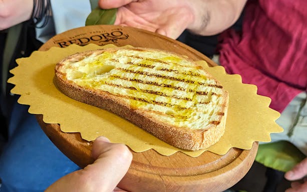 Grilled bread with olive oil served on a wooden platter during a Verona food tour.