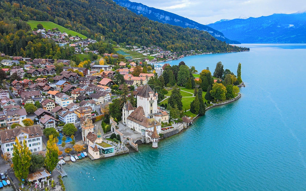 Castle Oberhofen on Lake Thun with surrounding village and mountains.