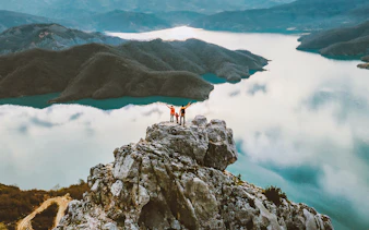 Family hiking on Gamti mountain summit with lake and hills in the background.