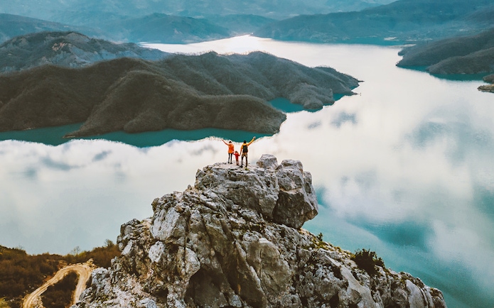 Family hiking on Gamti mountain summit with lake and hills in the background.