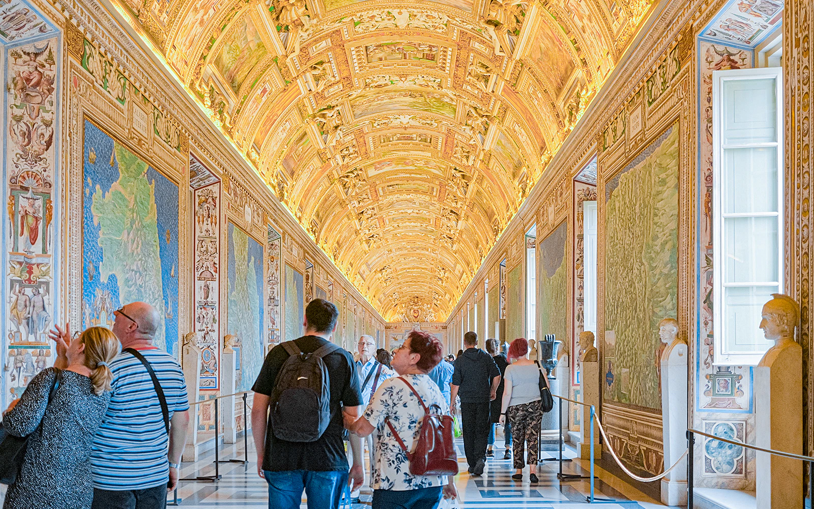 Visitors exploring the ornate Gallery of Maps at the Vatican Museum.