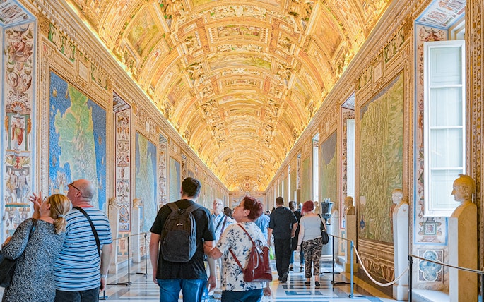 Visitors exploring the ornate Gallery of Maps at the Vatican Museum.