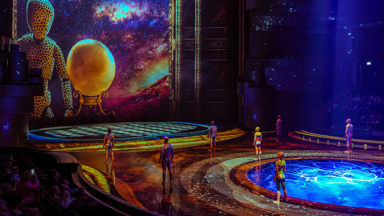 Performers on stage at La Perle show in Dubai with vibrant backdrop and water feature.
