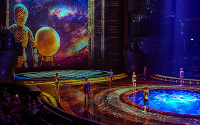 Performers on stage at La Perle show in Dubai with vibrant backdrop and water feature.