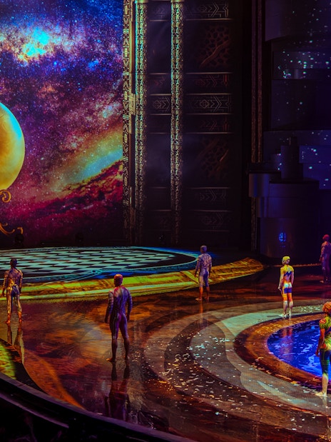 Performers on stage at La Perle show in Dubai with vibrant backdrop and water feature.