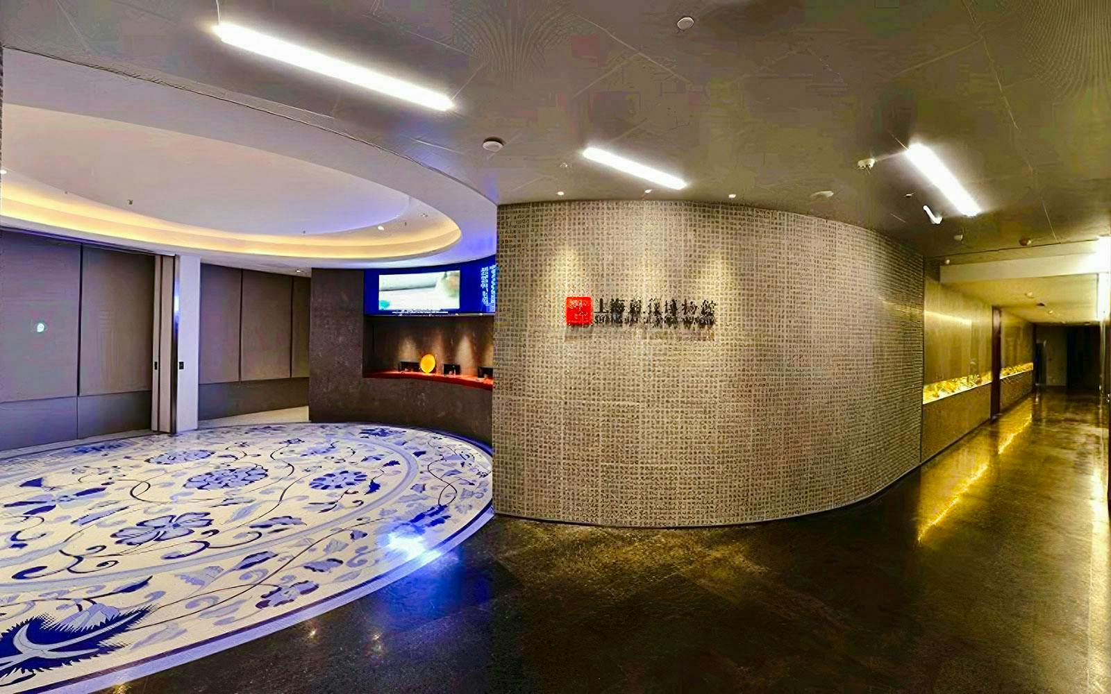 Entrance of Shanghai Guanfu Museum with decorative floor and illuminated wall display.