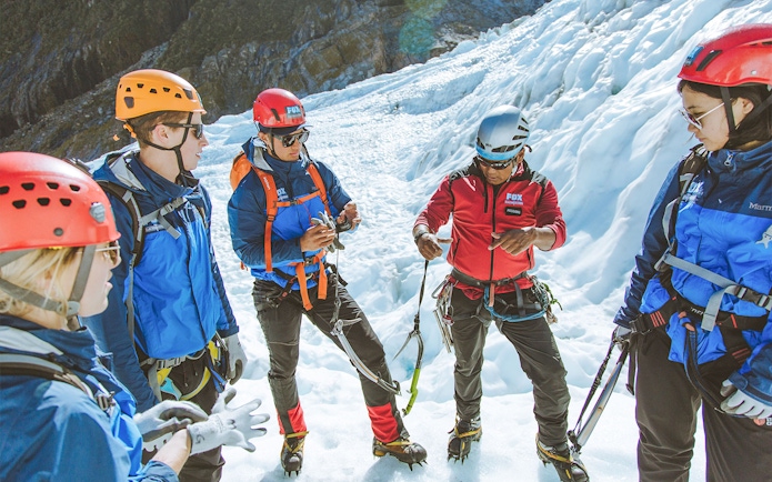Group preparing for Fox Glacier heli hike with guide on snowy terrain.