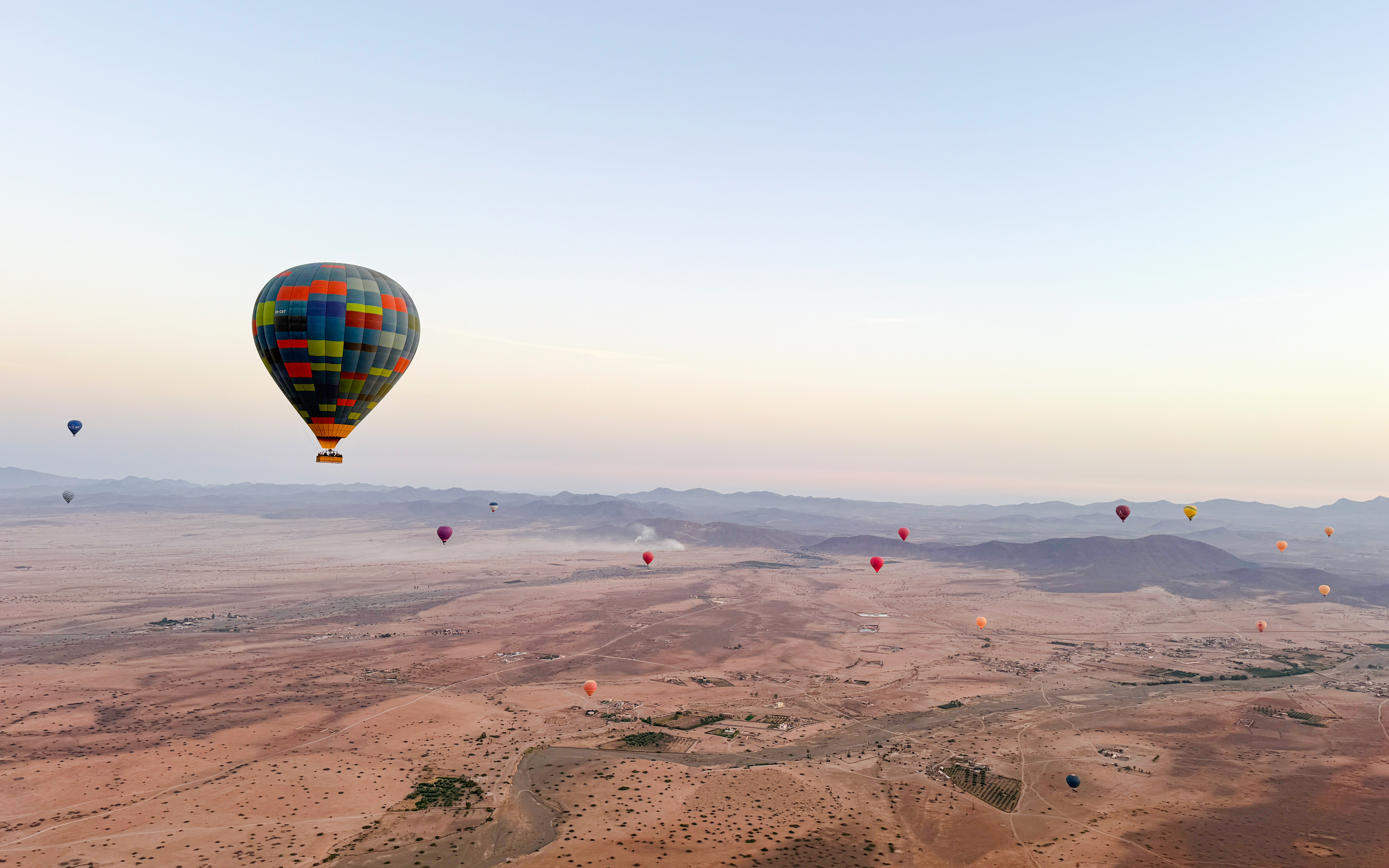 Hot air balloons over desert landscape near Marrakech at sunrise.