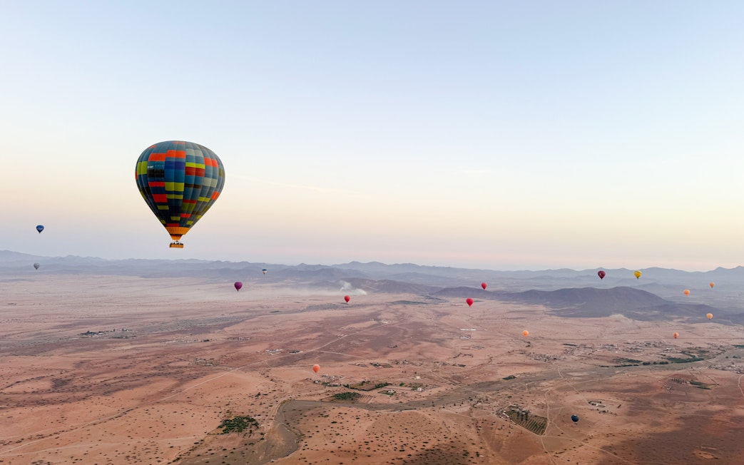 Hot air balloons over desert landscape near Marrakech at sunrise.