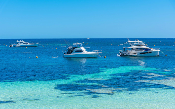 Boats moored in clear waters at Rocky Bay, Rottnest Island, Australia.