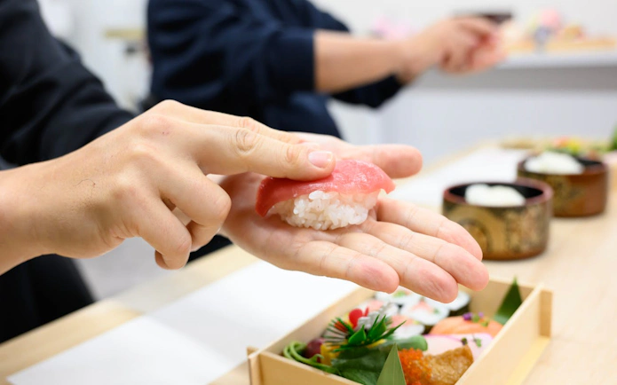 Hand crafting sushi with tuna slice during Tsukiji Market tour.