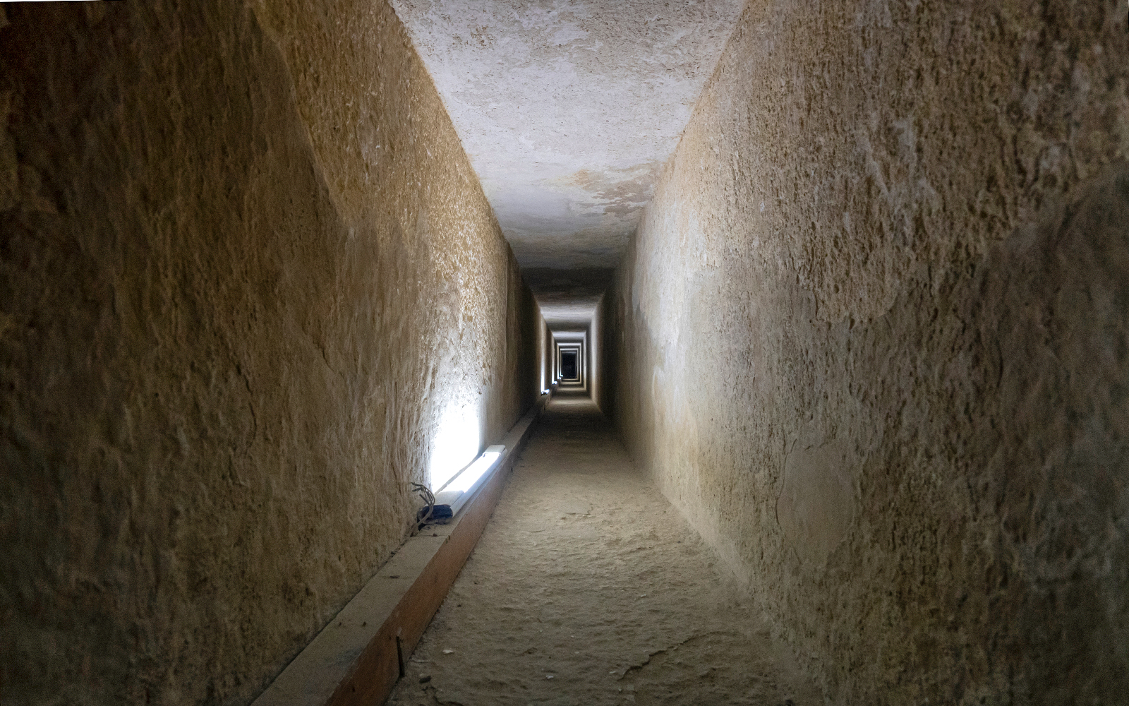 Tunnel entrance to ancient Egyptian pyramid with hieroglyphics on walls.