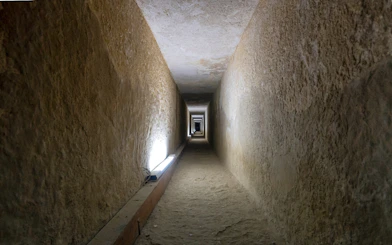 Tunnel entrance to ancient Egyptian pyramid with hieroglyphics on walls.