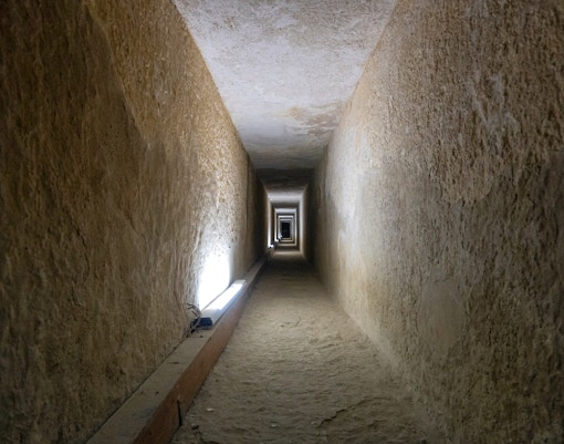 Tunnel entrance to ancient Egyptian pyramid with hieroglyphics on walls.