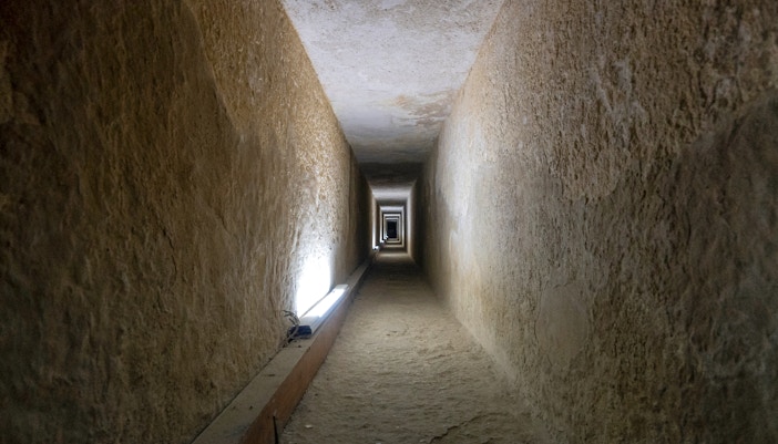 Tunnel entrance to ancient Egyptian pyramid with hieroglyphics on walls.