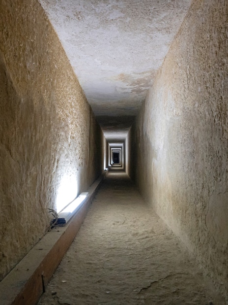 Tunnel entrance to ancient Egyptian pyramid with hieroglyphics on walls.
