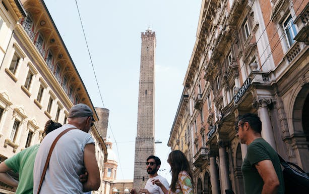 Group on a guided food tour near Asinelli Tower in Bologna.