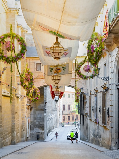 Street in Toledo old town, Spain with hanging decorations and historic buildings.