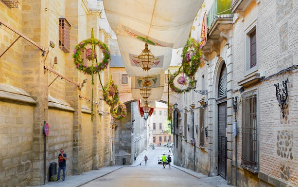Street in Toledo old town, Spain with hanging decorations and historic buildings.