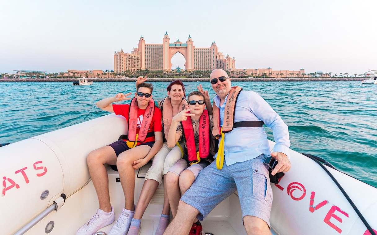 Tourists on a boat tour in Dubai with Atlantis The Palm in the background.