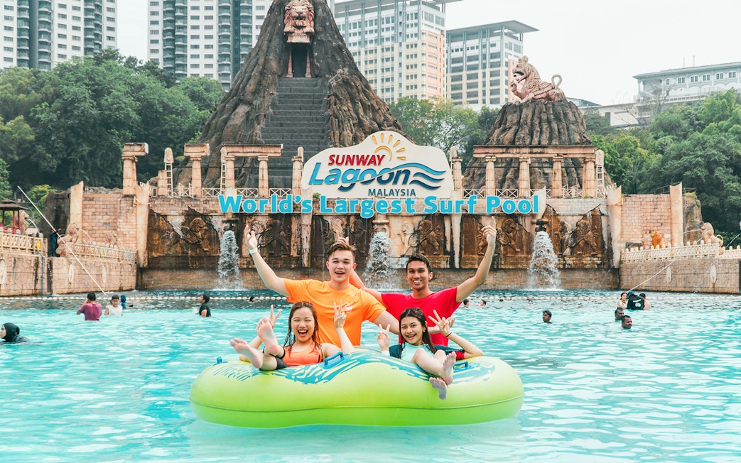 Family enjoying a float ride at Sunway Lagoon's surf pool, Malaysia.