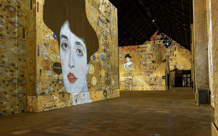 Immersive art projections at Fabrique des Lumières featuring Klimt's portraits.