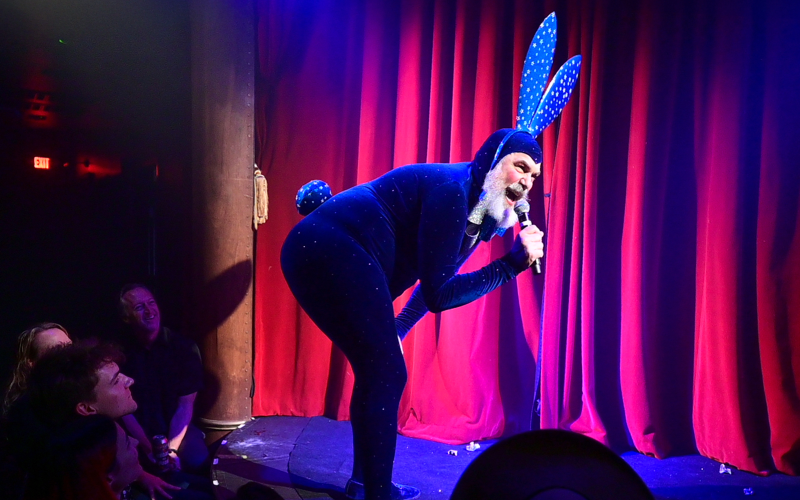 Performer in blue costume with bunny ears on stage at Miss Behaves: Maverick's Variety Show.